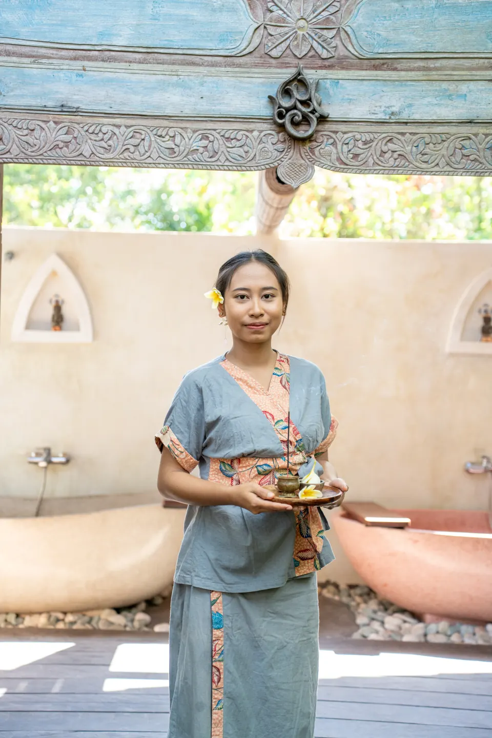 A member of the spa team holding a tray of preparations beside the bath rooms
