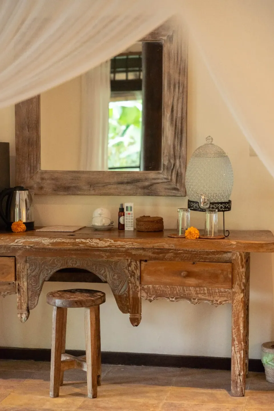 A wooden dressing table and mirror beneath canopy curtains