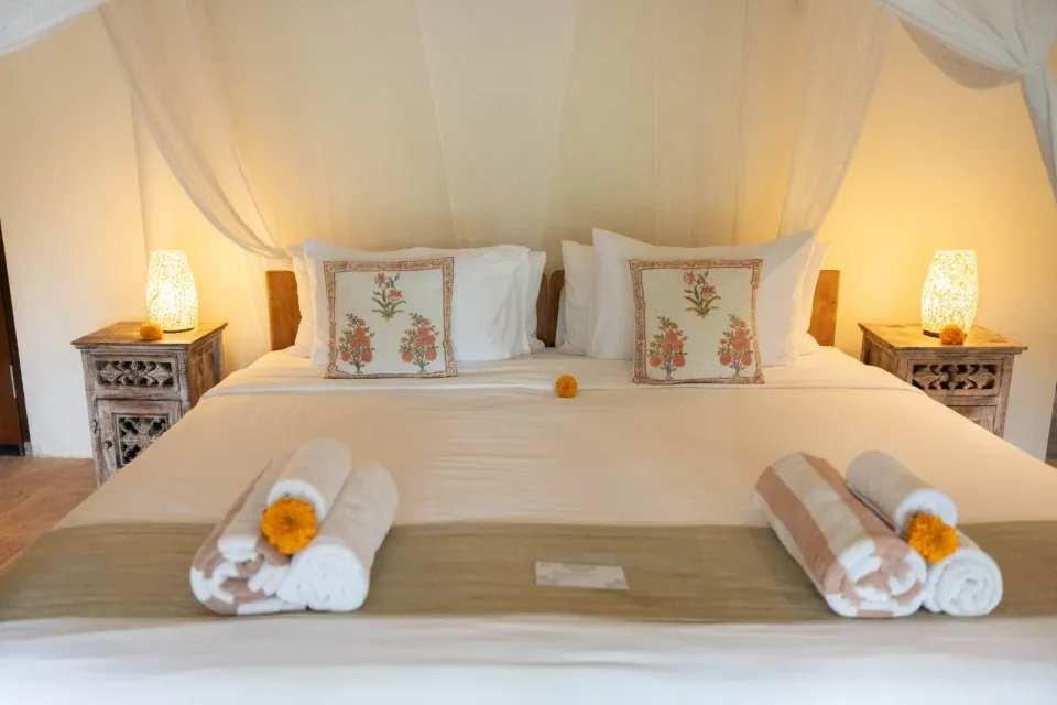 A double bed with a light canopy and bedside lamps