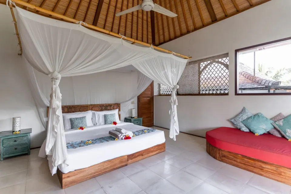 A canopy bed and corner daybed beneath a pitched timber roof